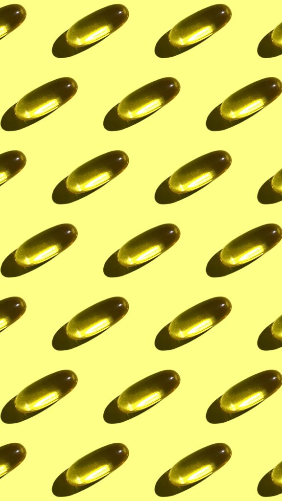 A vivid repetition of gelatin capsules creating a geometric pattern on a bright yellow background.